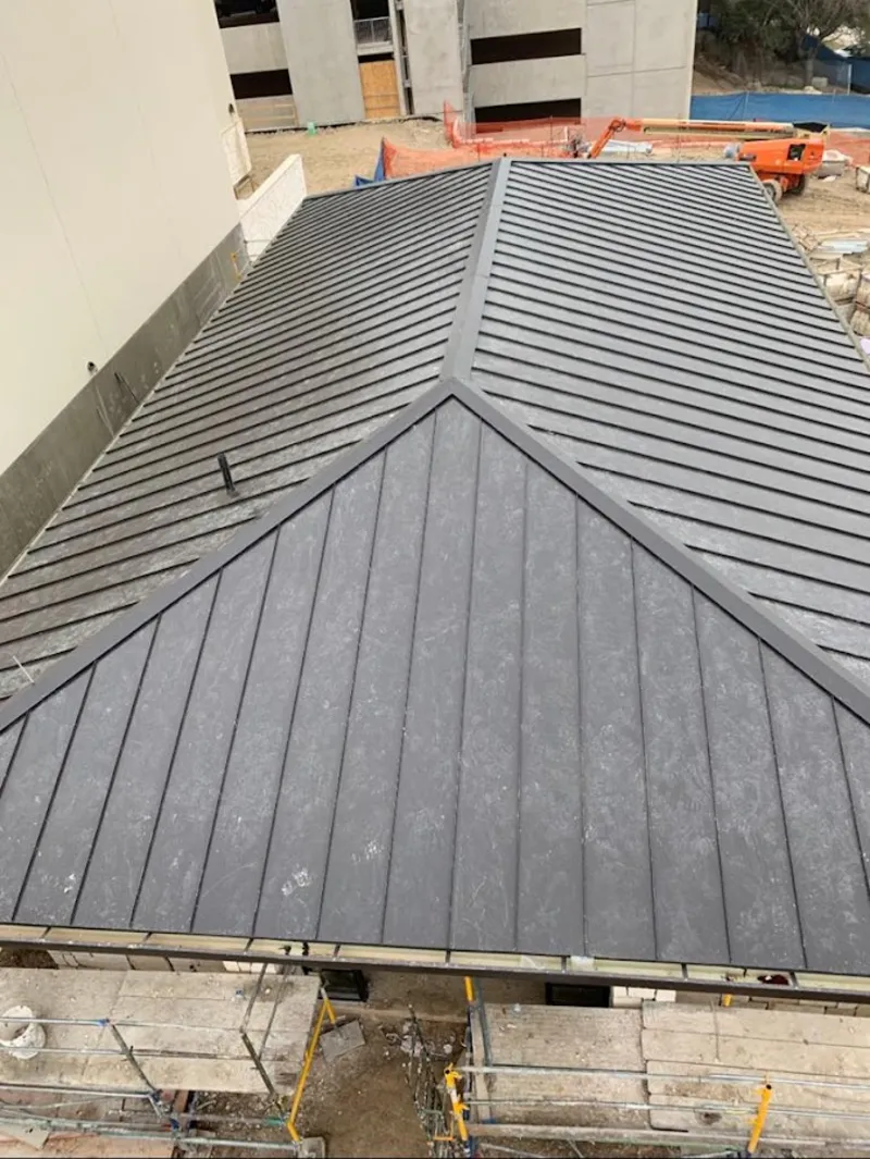 Commercial metal roof construction with crane equipment in Becker